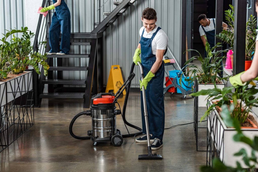 young-cleaner-cleaning-floor-with-vacuum-cleaner